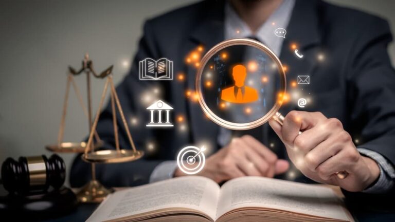 Man in suit holds a magnifying glass over a book with symbols of law and justice.