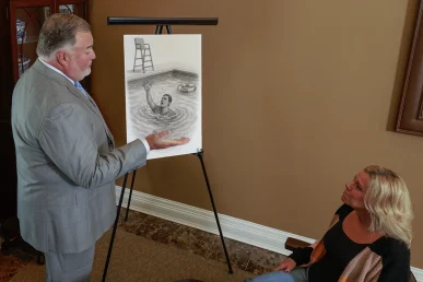 Attorney joel hamner discusses a drowning accident exhibit with a client, covering pool safety failures.