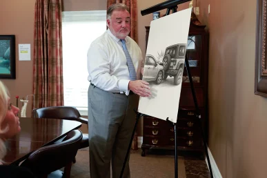 Attorney joel hamner discusses a rear end crash exhibit with a client, highlighting braking distance data.
