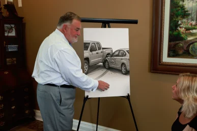 Attorney joel hamner discusses a side swipe accident exhibit with a client, highlighting lane change diagrams.