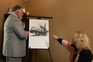 Attorney joel hamner discusses an airplane accident exhibit with a client, highlighting flight path details and safety reports.