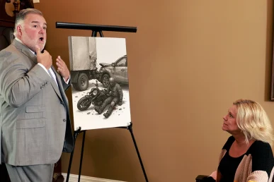 Attorney joel hamner discusses an amputation injury exhibit with a client, highlighting surgical records and prosthetic care plans.