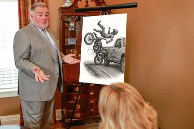Attorney joel hamner examines a dirt bike accident exhibit with a client, detailing trail conditions and impact analysis.