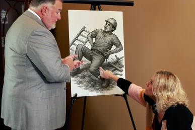 Attorney joel hamner explains a back injury exhibit to a client, pointing out mri scans and treatment notes.