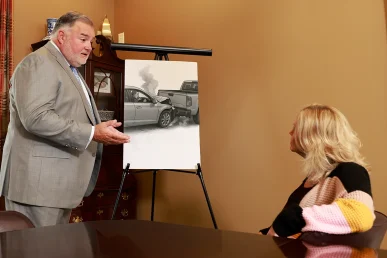Attorney joel hamner explains a brake failure exhibit to a client, focusing on mechanical inspection reports.