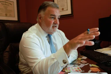Attorney joel hamner explains a cervical injury exhibit to a client, showing x rays and therapy plans.