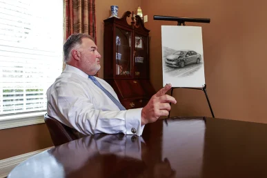 Attorney joel hamner explains a hit and run accident exhibit to a client, pointing to surveillance images.