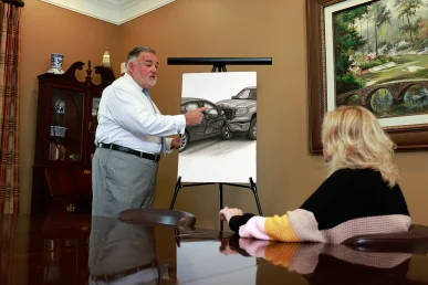 Attorney joel hamner explains a passenger injury exhibit to a client, highlighting seat belt evidence.
