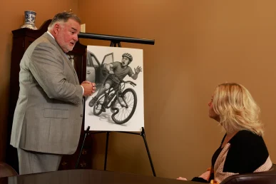 Attorney joel hamner meets with a client to examine a bicycle accident exhibit showing driver negligence and road conditions.