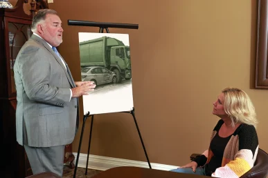 Attorney joel hamner presents a garbage truck accident exhibit to a client, mapping routes and collision points.