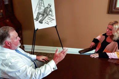 Attorney joel hamner presents a spinal cord injury exhibit to a client, featuring mri scans and rehab plans.
