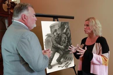 Attorney joel hamner reviews a farm accident exhibit with a client, focusing on equipment safety data.