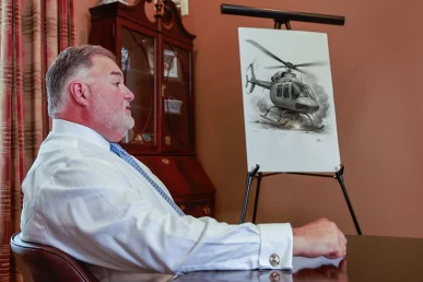 Attorney joel hamner reviews a helicopter accident exhibit with a client, featuring flight path graphics.
