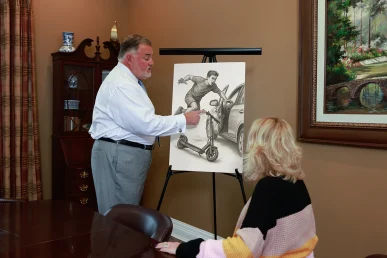 Attorney joel hamner reviews a scooter accident exhibit with a client, highlighting rider impact analysis.