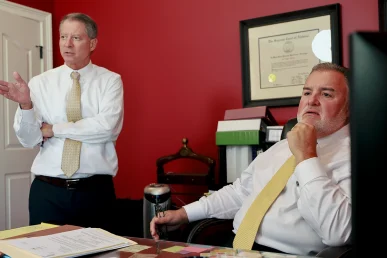 Attorneys tom mccutcheon and joel hamner meet with a client about pursuing damages for a severe injury.