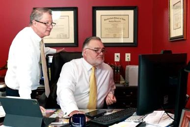 Attorneys tom mccutcheon and joel hamner meet with a client in joel’s office to discuss an amazon prime delivery accident case.