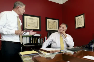 Attorneys tom mccutcheon and joel hamner review diagnostic scans with a client for a whiplash and neck injury case.