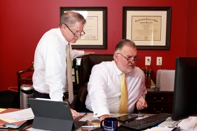 Attorneys tom mccutcheon and joel hamner sit with a client reviewing medical records for a potential amputation injury claim.