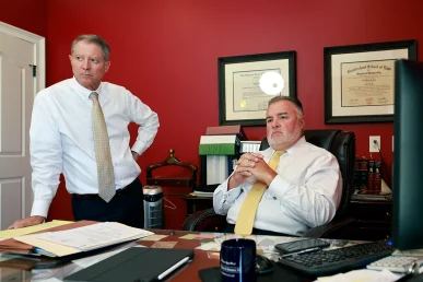 Attorneys tom mccutcheon and joel hamner talk with a client about a strains and contusions injury claim.