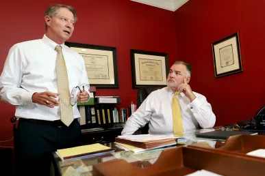 Attorneys tom mccutcheon and joel hamner talk with a client about a vision loss case caused by an accident.