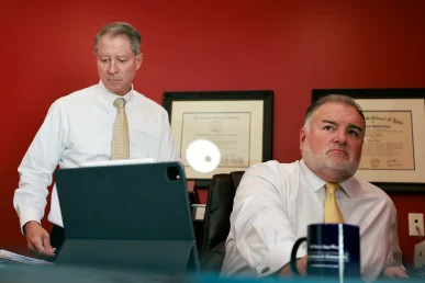Attorneys tom mccutcheon and joel hamner talk with a client regarding a potential dhl delivery accident lawsuit.