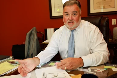 Lawyer joel hamner explains an automotive defects exhibit to a client, outlining recalled parts and inspection findings.