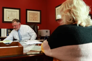Lawyer joel hamner reviews a defective airbag exhibit with a client, showing recall documentation.