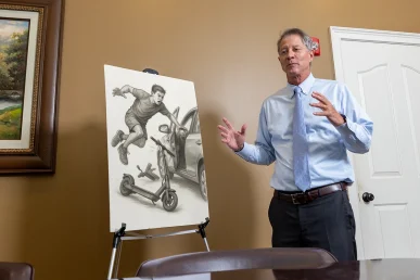 Lawyer tom mccutcheon discusses a scooter accident exhibit depicting rider trajectory and impact zone.