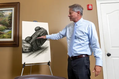 Lawyer tom mccutcheon examines a rollover accident exhibit with vehicle stability graphics.