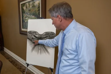 Lawyer tom mccutcheon reviews a head on collision exhibit, pointing out skid marks and impact angles.