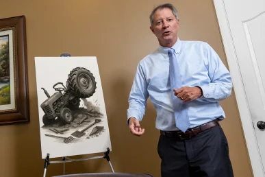 Lawyer tom mccutcheon reviews a tractor accident exhibit showing field equipment malfunction.