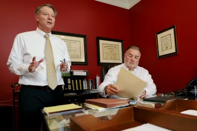 Tom mccutcheon and joel hamner meet with a client to review a usps mail truck accident claim.