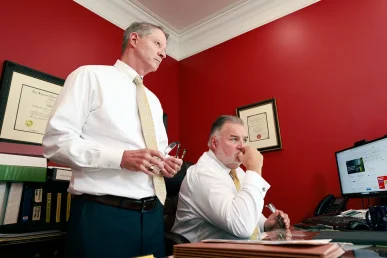 Tom mccutcheon and joel hamner sit with a client to evaluate a garbage truck accident case.