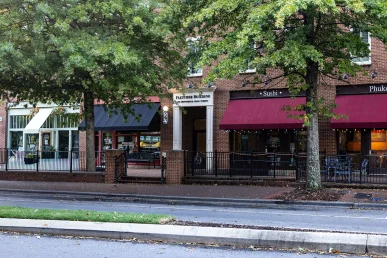 Fletcher Building on Main Street in Huntsville, featuring storefronts for Sushi and Phuket, surrounded by trees.