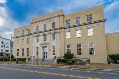 Historic Huntsville federal courthouse viewed from the front left angle, featuring a staircase and landscaped shrubs.