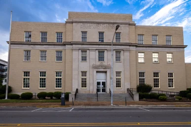 Historic Huntsville federal courthouse features a large entrance with steps and a light-colored brick facade under a cloudy.