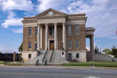 Limestone County Courthouse features a grand entrance with columns, stairs, and a clock under a blue sky.