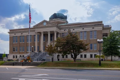 Limestone County Courthouse with a blue car parked nearby, featuring stairs, trees, and an American flag.