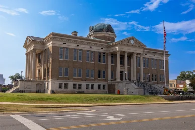Limestone County Courthouse in autumn, showcasing its classic architecture and surrounding greenery under a blue sky.