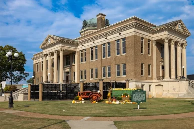 Limestone County Courthouse side view with a vintage tractor display and decorative pumpkins in the foreground.