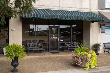 Front of McCutcheon & Hamner law office in Athens, Alabama, featuring a green-striped awning and flower planters.