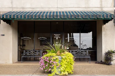 The entrance of McCutcheon & Hamner's office in Athens, Alabama, featuring a green striped awning and flower planter.