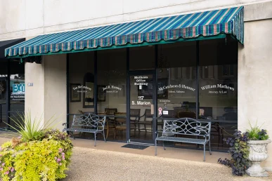 The entrance of McCutcheon & Hamner law office in Athens, Alabama, features a striped awning and seating outside.