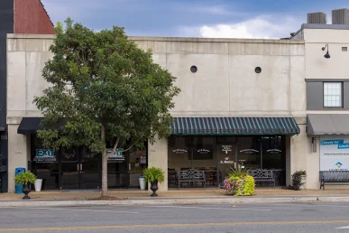 McCutcheon and Hamner's offices in Athens, Alabama, featuring a green striped awning and a tree in front.