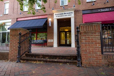 The Fletcher Building at 475 Providence Main Street in Huntsville, flanked by shops and decorative brickwork.