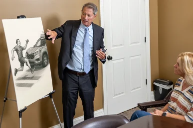 Tom McCutcheon explains a pedestrian accident case to a client in his office in Huntsville, using a visual aid.