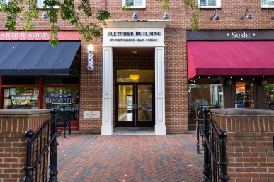 The entryway of Fletcher Building at 475 Providence Main Street, flanked by Roosters and a sushi restaurant.