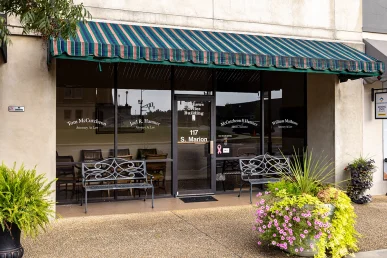 Exterior of Tom and Joel's law office in Athens, Alabama, featuring glass doors, bench seating, and decorative plants.