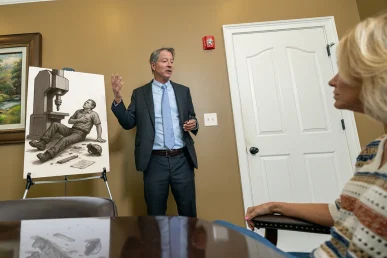 Tom McCutcheon discusses a workers’ compensation claim with a client in Huntsville, Alabama, with a visual aid.