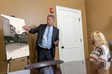 Tom McCutcheon discusses a car accident case with a client, reviewing evidence in a meeting room in Athens, Alabama.
